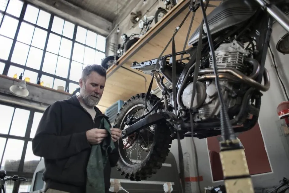 Moto sur banc de contrôle technique, technicien vérifiant les équipements