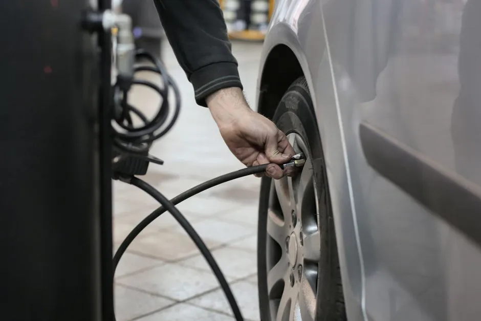 Gonfleur numérique branché sur une prise 12 V, pneu de voiture en arrière-plan dans un garage