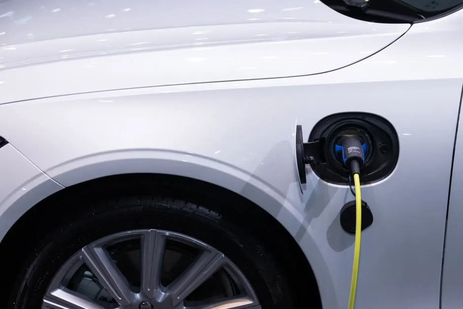 Borne de recharge murale et câble Type 2 branché sur une voiture électrique blanche